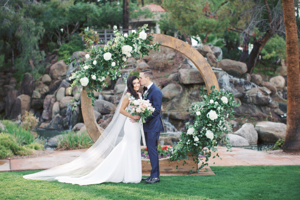 Circle arch with white floral and greenery at Arizona spring wedding featuring whimsical soft palette florals by Array Design, Phoenix, Arizona. Val Vista Lakes venue and Melissa Jill photography.