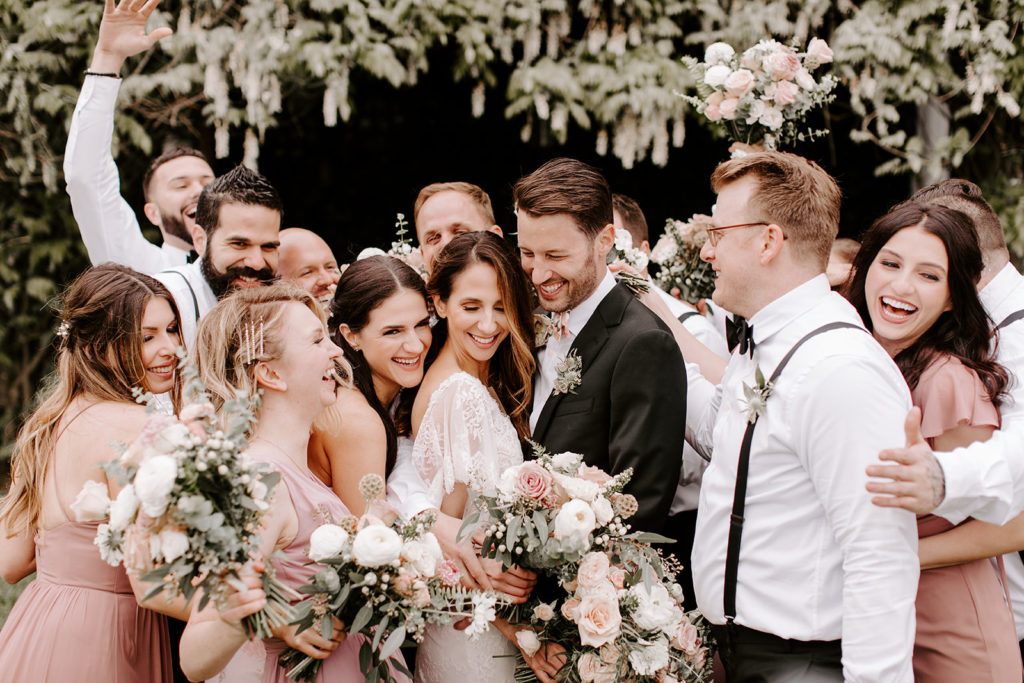 Romantic Southern California mountain wedding at Sacred Mountain Julian. Beautiful blush wedding flowers with complimenting white in bridal and bridesmaid bouquets with greenery throughout the celebration.