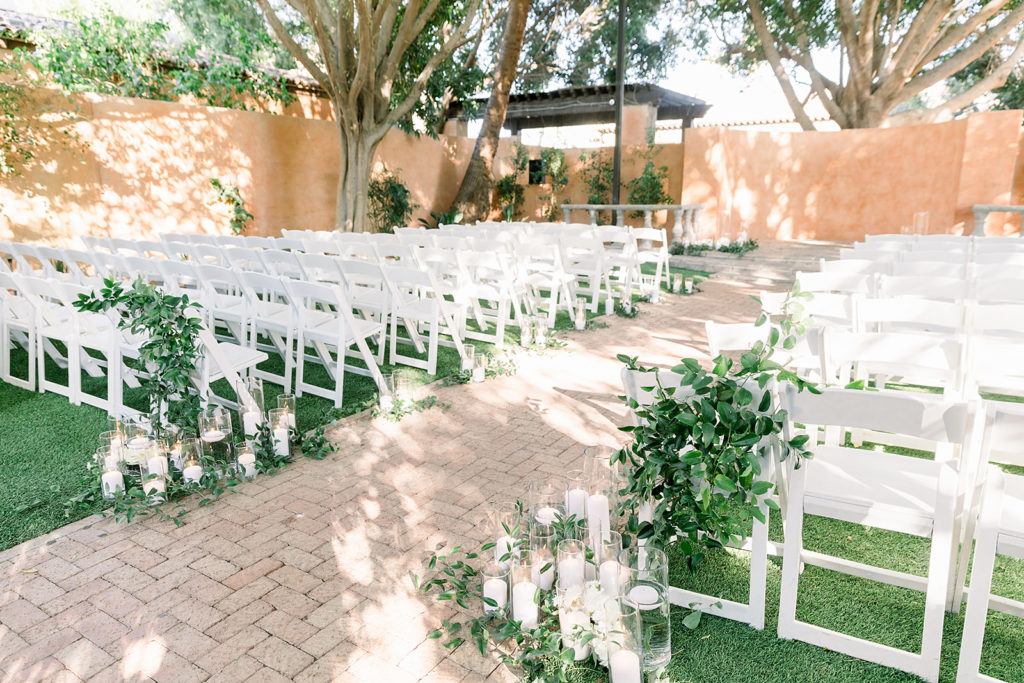 Ceremony aisle candles and greenery at Arizona wedding Phoenix venue, Royal Palms. Stylish celebration featuring white wedding flowers and greenery with pillar candles featured in reception and ceremony. Floral arrangements by Array Design. Photography by Jessica Q.