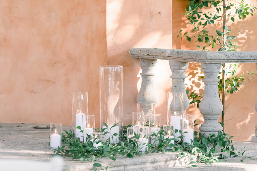Ceremony pillar candles with greenery at Arizona wedding Phoenix venue, Royal Palms. Stylish celebration featuring white wedding flowers and greenery with pillar candles featured in reception and ceremony. Floral arrangements by Array Design. Photography by Jessica Q.