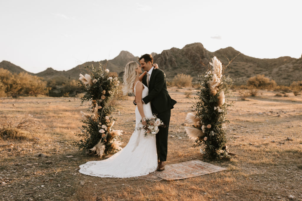 Boho Arizona Desert Ceremony - the perfect boho wedding flowers for an intimate desert wedding ceremony. The blush and white wedding flowers with dusty pink wedding color palette was seen in the wedding flower arrangements, ceremony decor, wedding bouquets, wedding ceremony backdrop outdoor, and wedding flowers. The boho wedding flowers included pampas grass, roses and greenery. Wedding ceremony altar of pampas grass, roses and greenery. Photos by Madi Robison. #weddingbouquets #desertwedding #weddingflowers #weddings