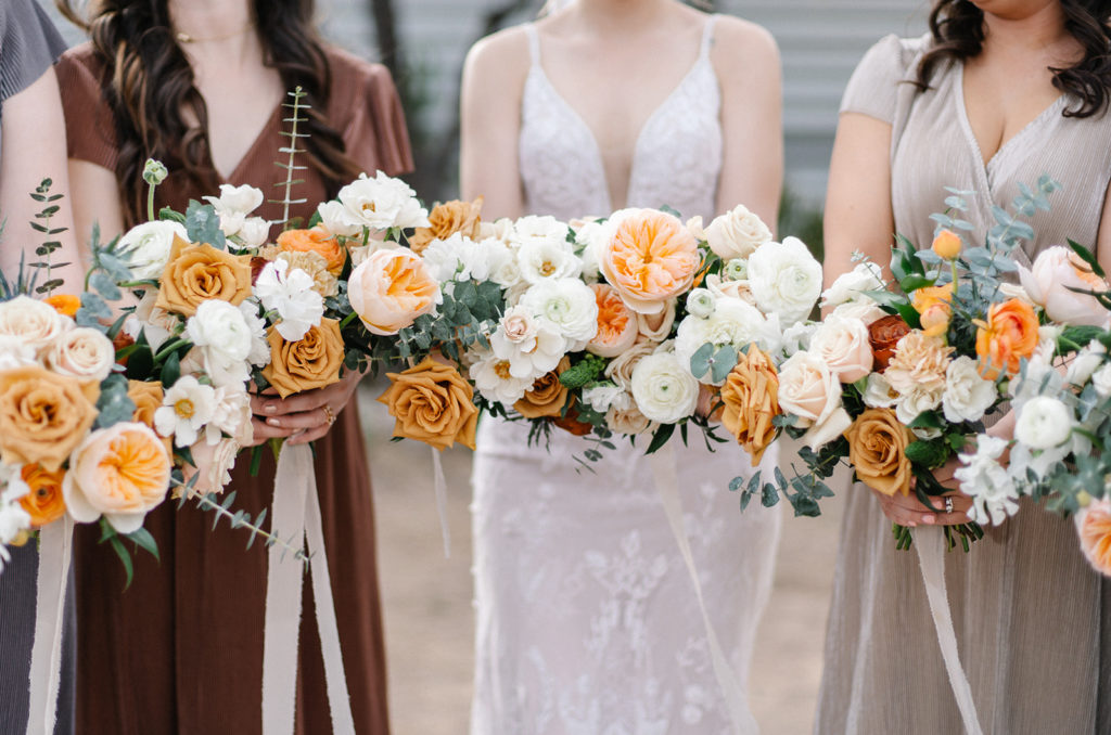 Arizona Modern Spring Wedding - the perfect bridesmaid bouquets at an elegant and modern urban wedding at The Venue on Washington in Phoenix. The gold wedding flowers with peach and white in the wedding color palette was seen in the wedding flower arrangements, bridal bouquet, bridesmaid bouquets, boutonniere, and bud vases of gold roses. The spring wedding flowers included roses, ranunculus, blue thistle, and greenery. Photos by Emily B. #wedding #springwedding #weddingflowers