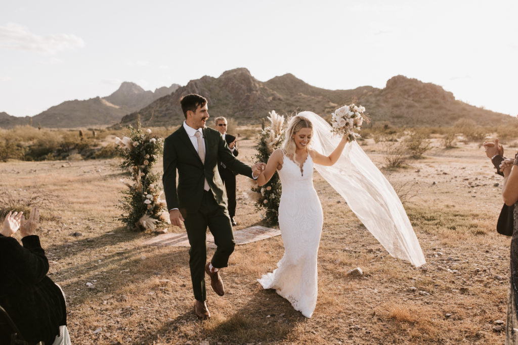 Boho Arizona Desert Ceremony - the perfect intimate Arizona desert wedding ceremony. The blush and white wedding flowers with dusty pink wedding color palette was seen in the wedding flower arrangements, ceremony decor, wedding bouquets, wedding ceremony backdrop outdoor, and wedding flowers. The boho wedding flowers included pampas grass, roses and greenery. Wedding ceremony altar of pampas grass, roses and greenery. Photos by Madi Robison. #weddingbouquets #desertwedding #weddingflowers #weddings