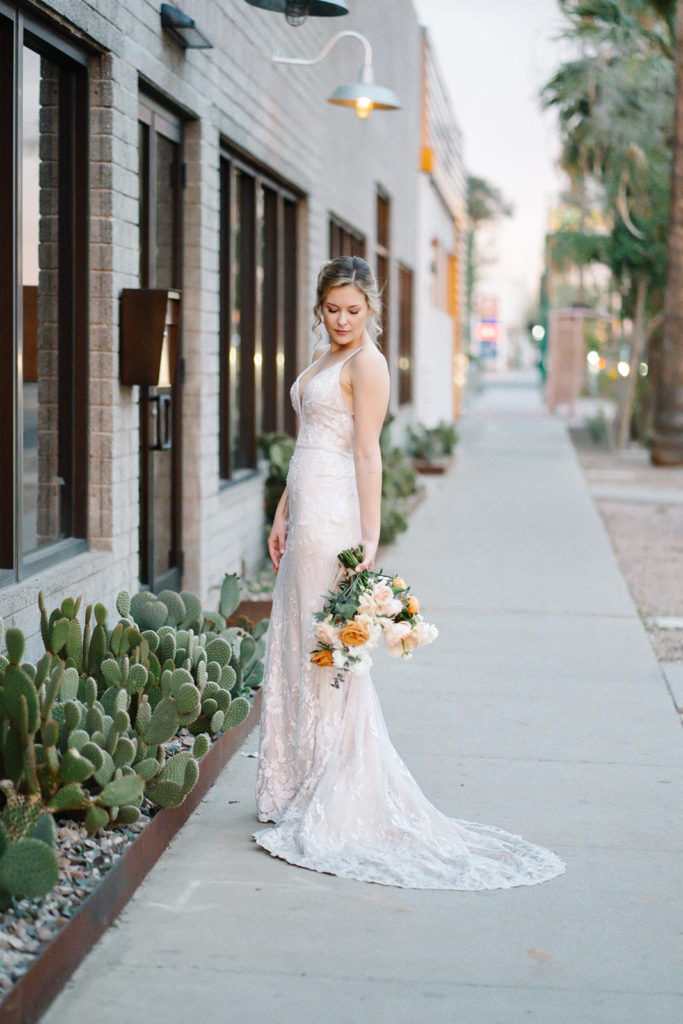 Arizona Modern Spring Wedding - the embroidered wedding dress at an elegant and modern urban wedding at The Venue on Washington in Phoenix. The gold wedding flowers with peach and white in the wedding color palette was seen in the wedding flower arrangements, bridal bouquet, bridesmaid bouquets, boutonniere, and bud vases of gold roses. The spring wedding flowers included roses, ranunculus, blue thistle, and greenery. Photos by Emily B. #wedding #springwedding #weddingflowers