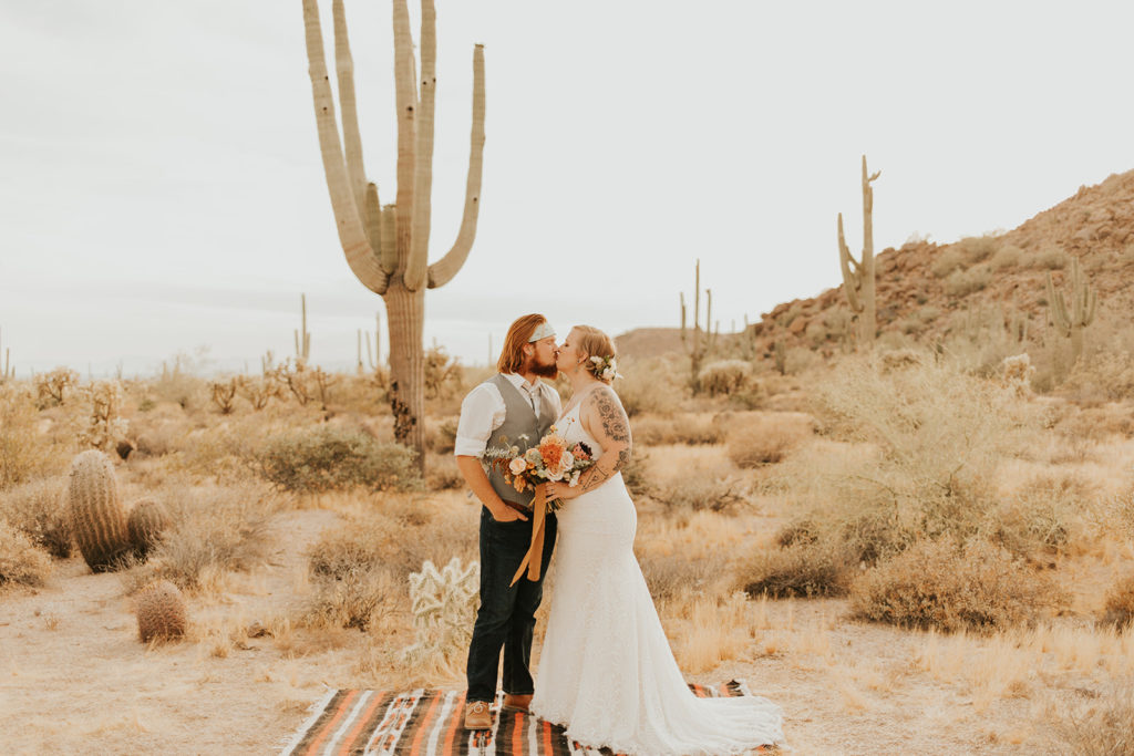 Wedding couple kissing in desert setting.