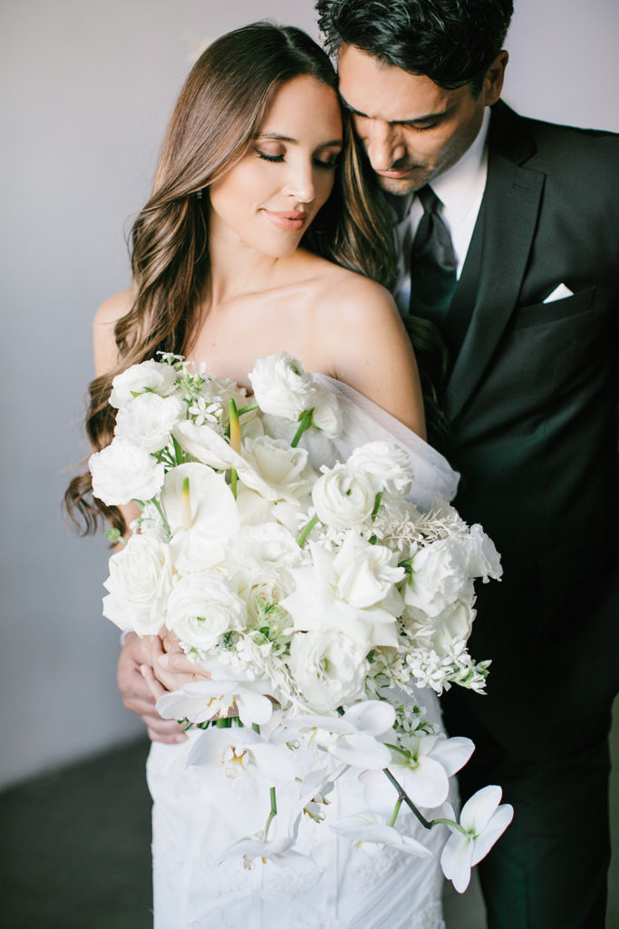 groom-huging-bride-holding-bouquet