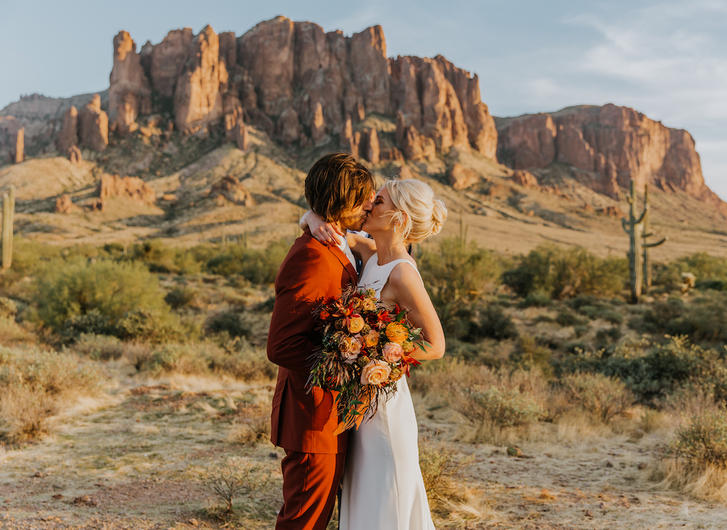 Bride and groom kissing in desert.