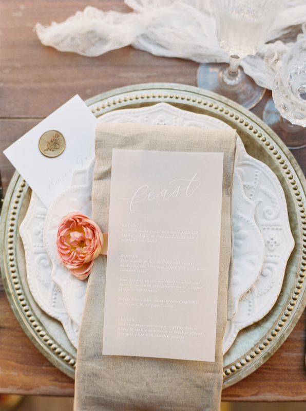 Taupe napkin at place setting with menu and pink flower.