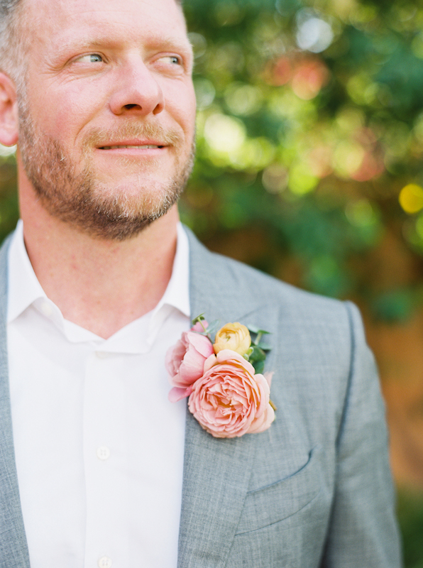 Pink flowers in boutonniere groom is wearing.