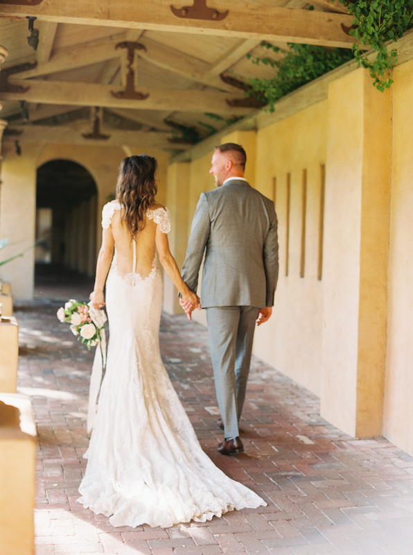 Bride and groom walking away in covered walkway at Royal Palms.