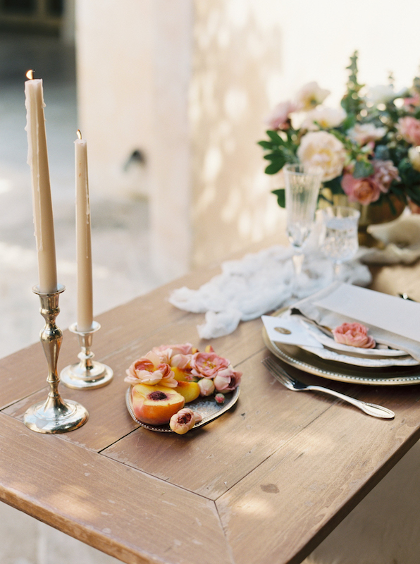 Candles, cut peaches, place setting and flowers on table.