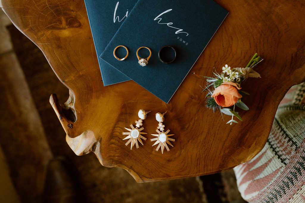 Vow books, wedding rings, bride's earrings, and boutonniere.