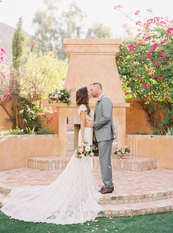 Bride and groom kissing in from of outdoor fireplace at Royal Palms.