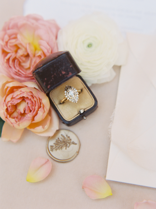 Wedding ring in box with pink, peach and white flowers.