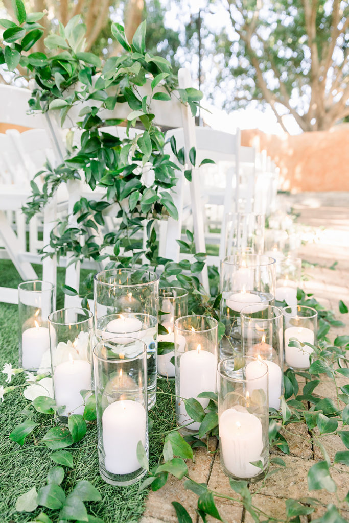 Outdoor wedding ceremony back aisle chair greenery and pillar candles.
