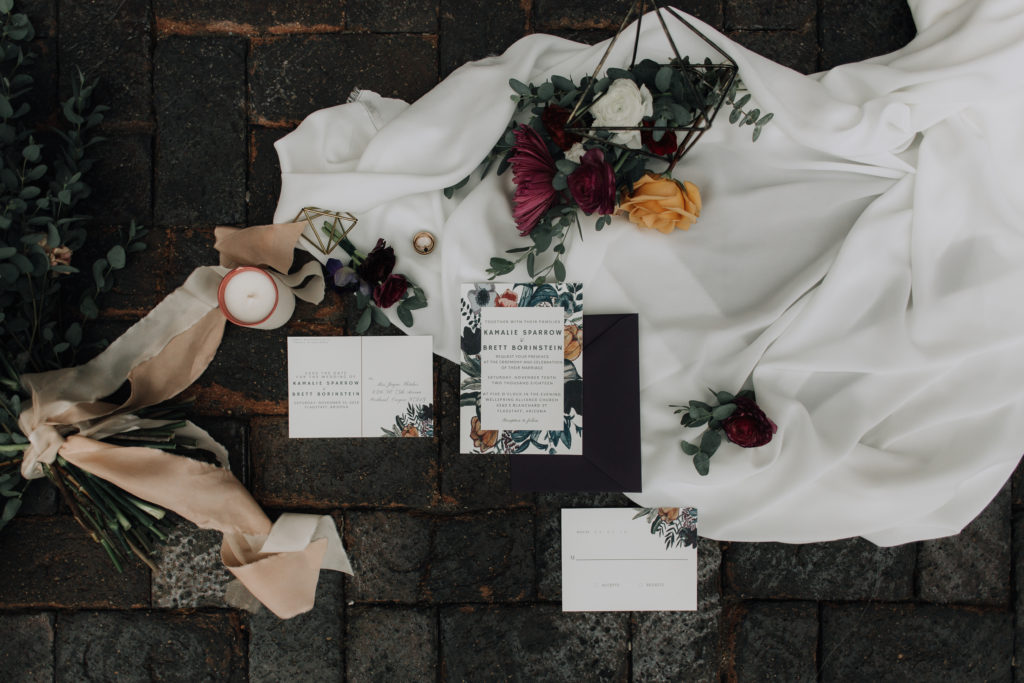 Wedding invitation flat lay on white fabric and brick.