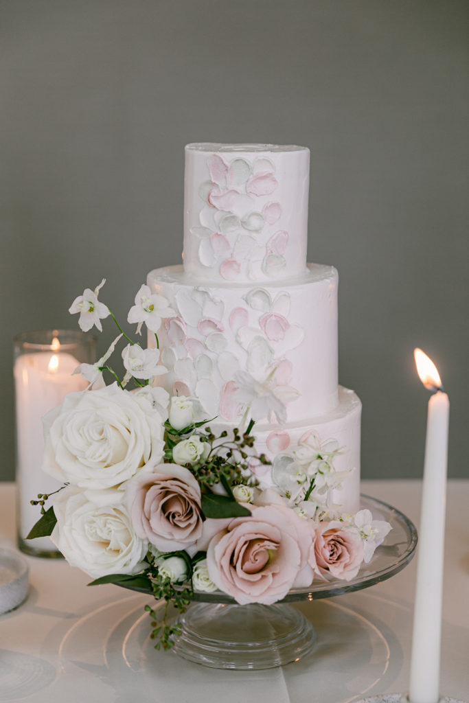 Three tier light pink wedding cake with flowers.