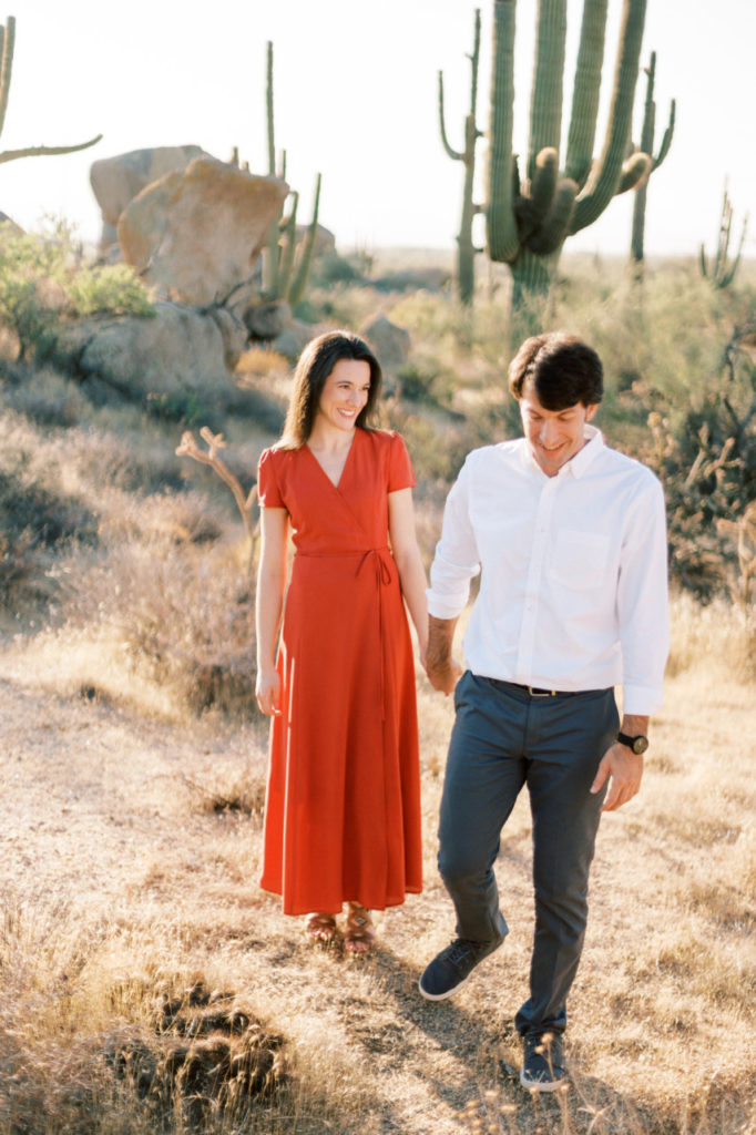 Woman and man holding hands walking in desert.