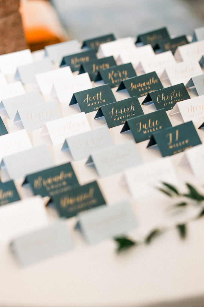 Wedding guest escort cards lined up on table on white and black paper.