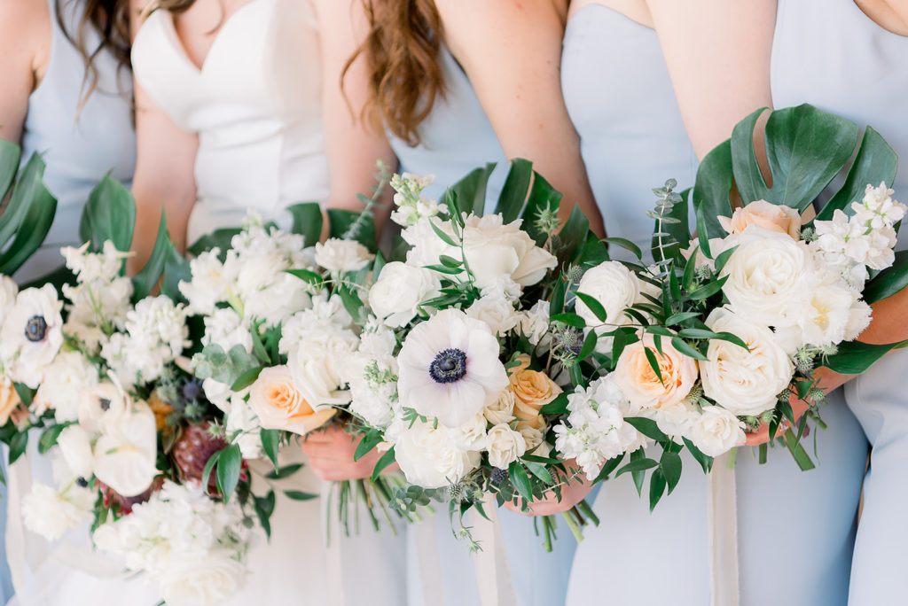Bride and bridesmaid bouquets with monstera leaves, anemone, white flowers.