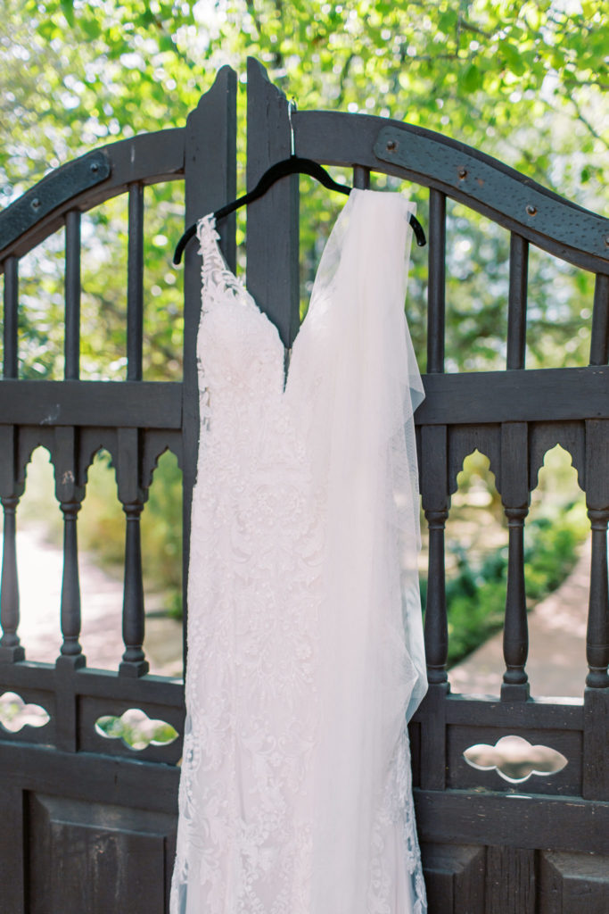 Bride's wedding dress on hanger, hanging from gate.