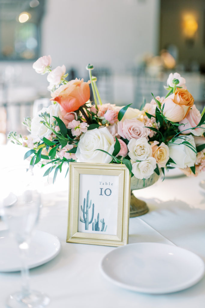 Wedding reception centerpiece with table number in frame in front.