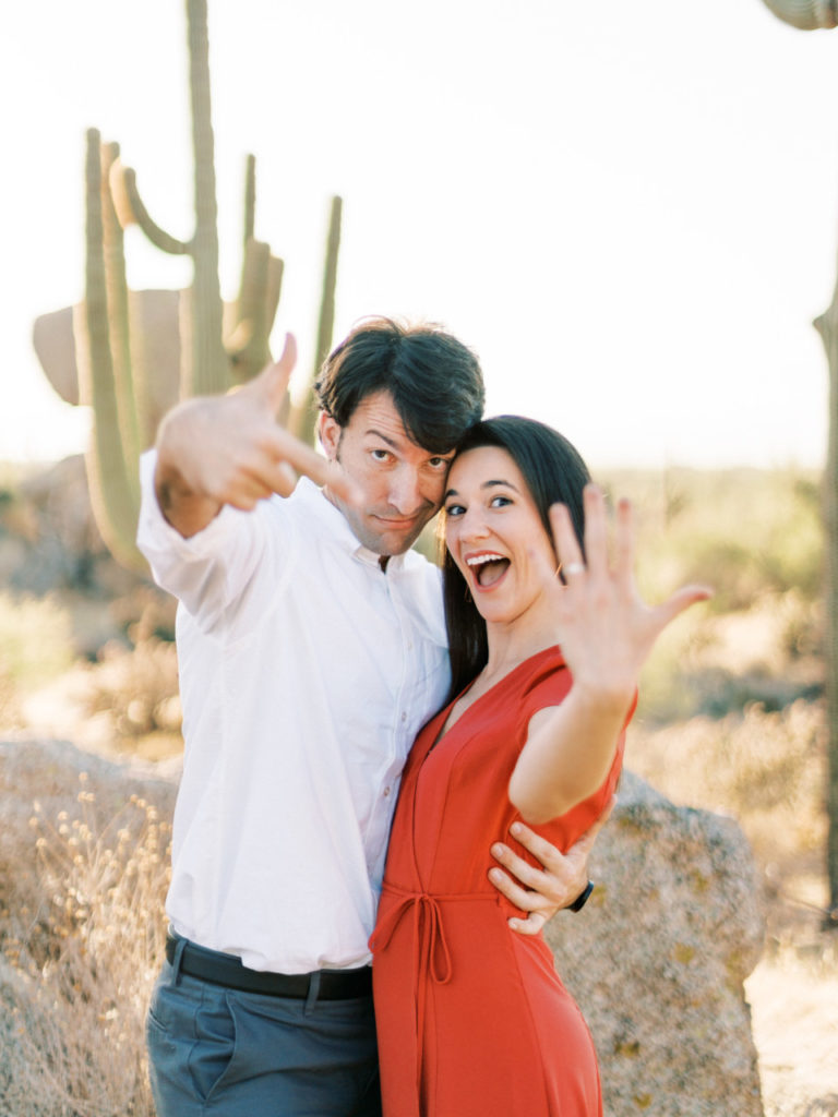 Couple celebrating engagement in desert setting.