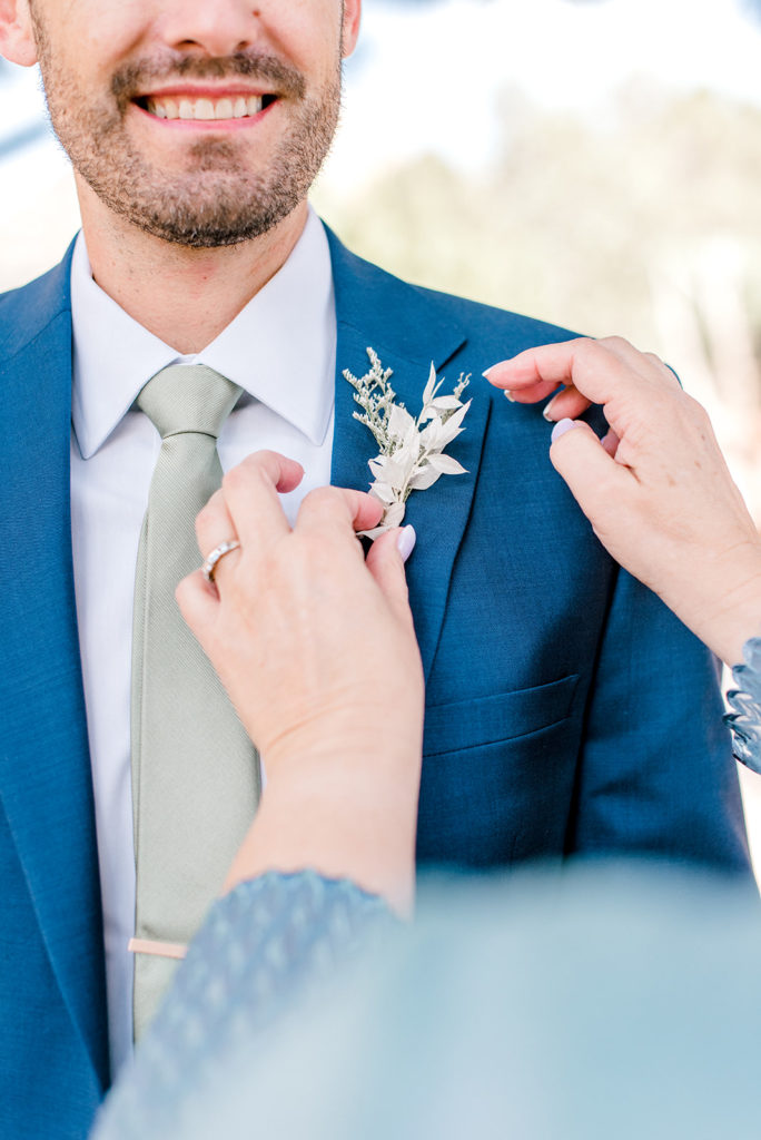 Groom getting his boutonniere pinned on by someone else.