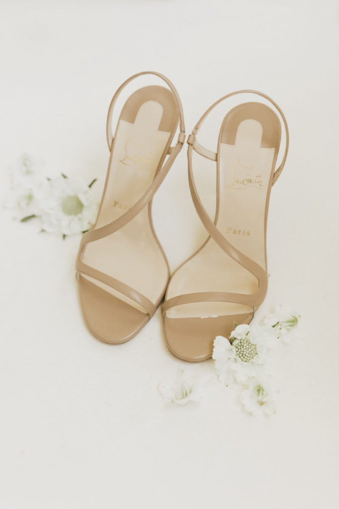 Tan bridal sandal pair with white scabiosa flowers next to them.