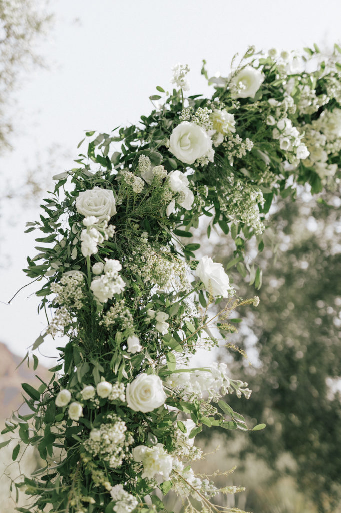 Close up of wedding ceremony arch of white flowers and greenery.