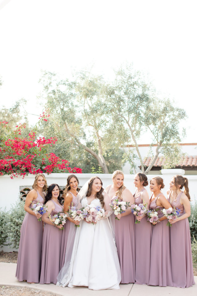 Bridesmaids lined up with bride, laughing, holding bouquets.