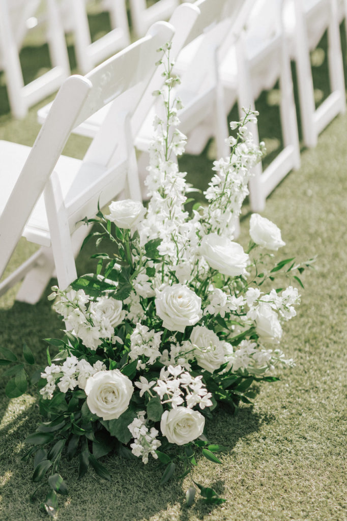 Back of wedding aisle white flowers ground arrangement.
