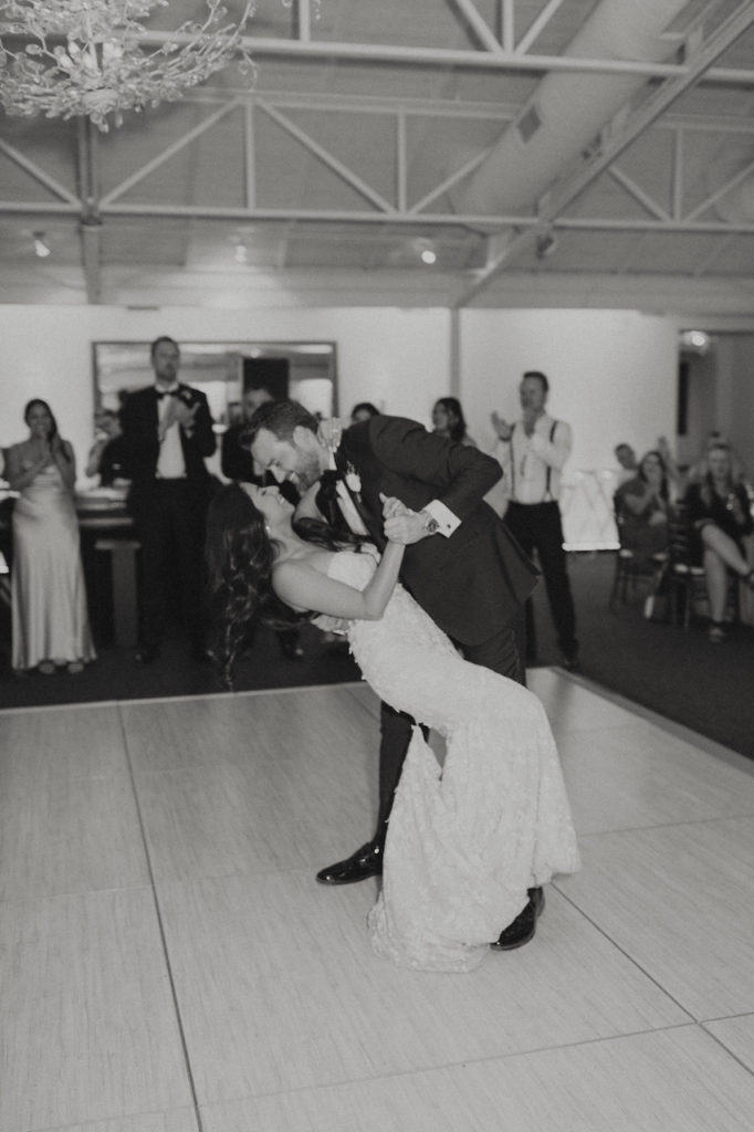Groom dipping bride during dance on inside dance floor.