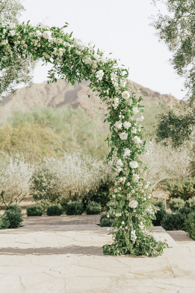 Arch details of white flowers and greenery at wedding ceremony.