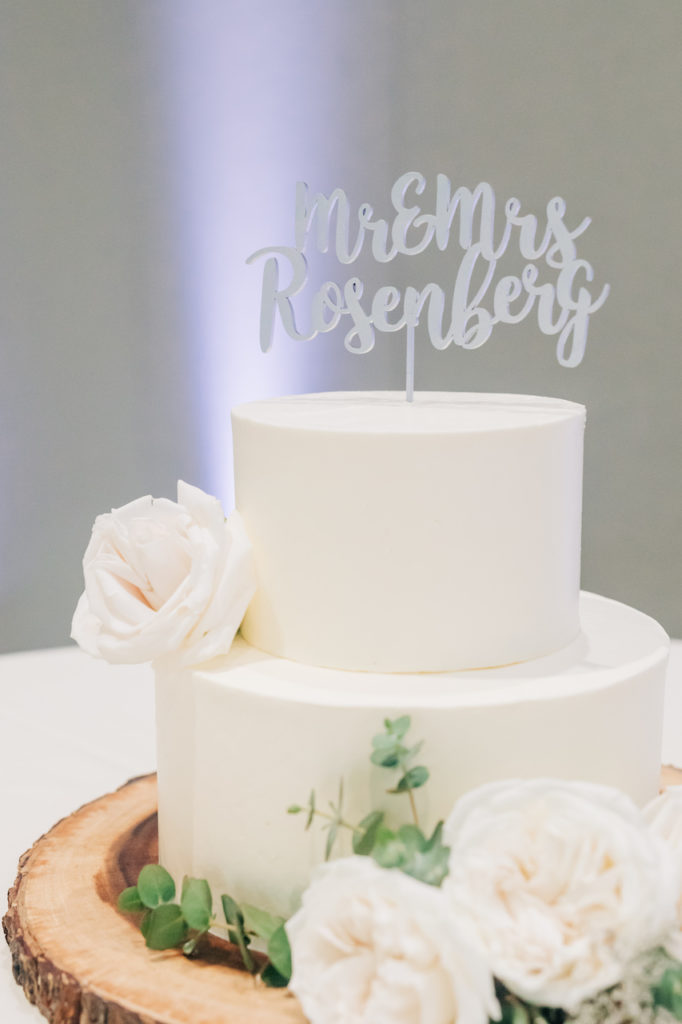Two layer white wedding cake with white flowers.