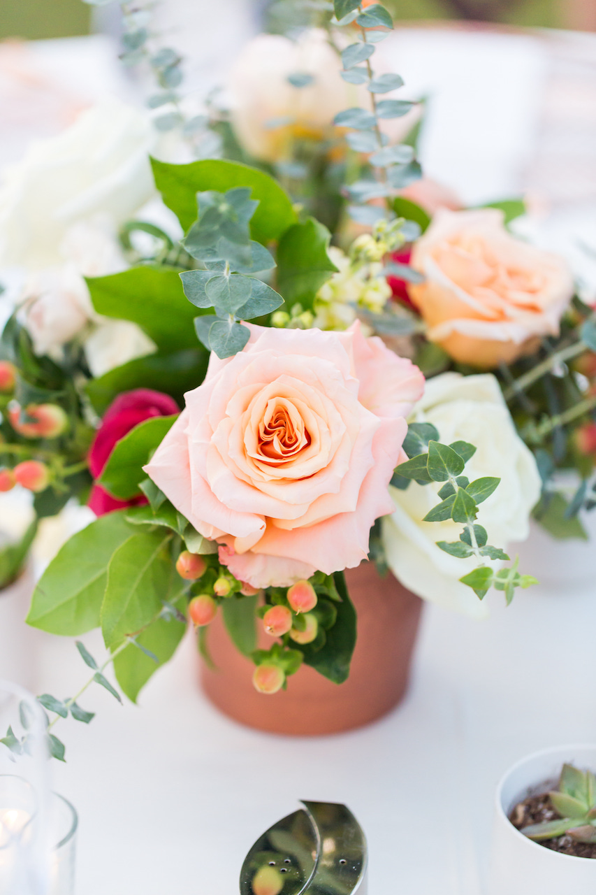 Wedding reception centerpiece of white, pink, and red roses and greenery.