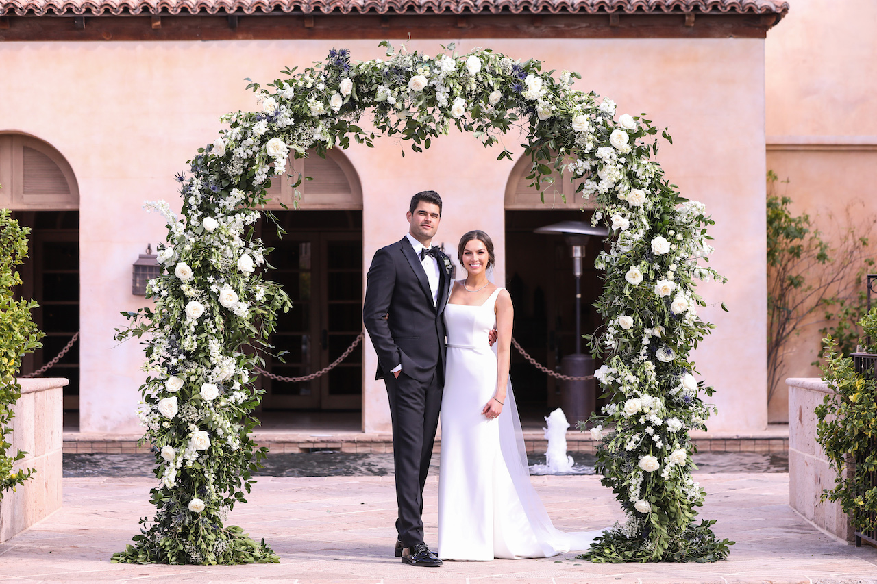 Royal Palms wedding ceremony arch of white flowers and greenery.
