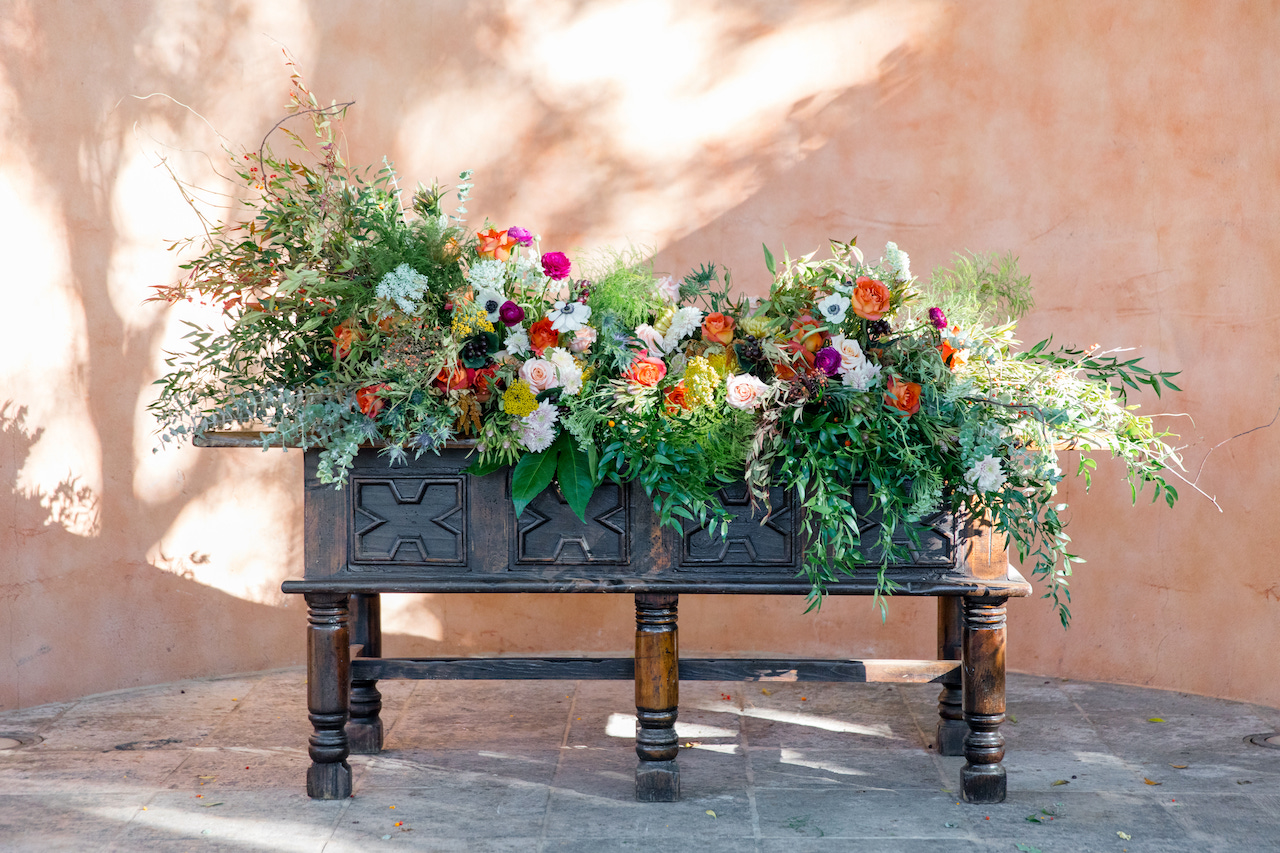 Front of ceremony large floral arrangement on antique wood table.