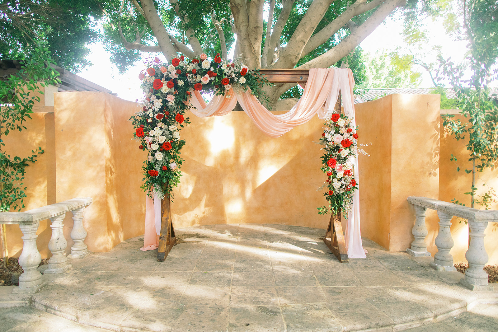 Wedding ceremony arch with floral installations and pink fabric.