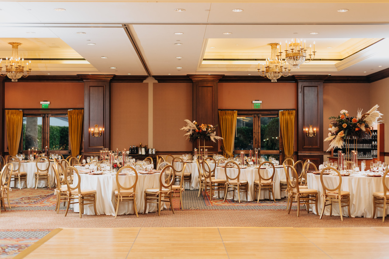 Indoor wedding reception at Omni resort with round tables, floral centerpieces.