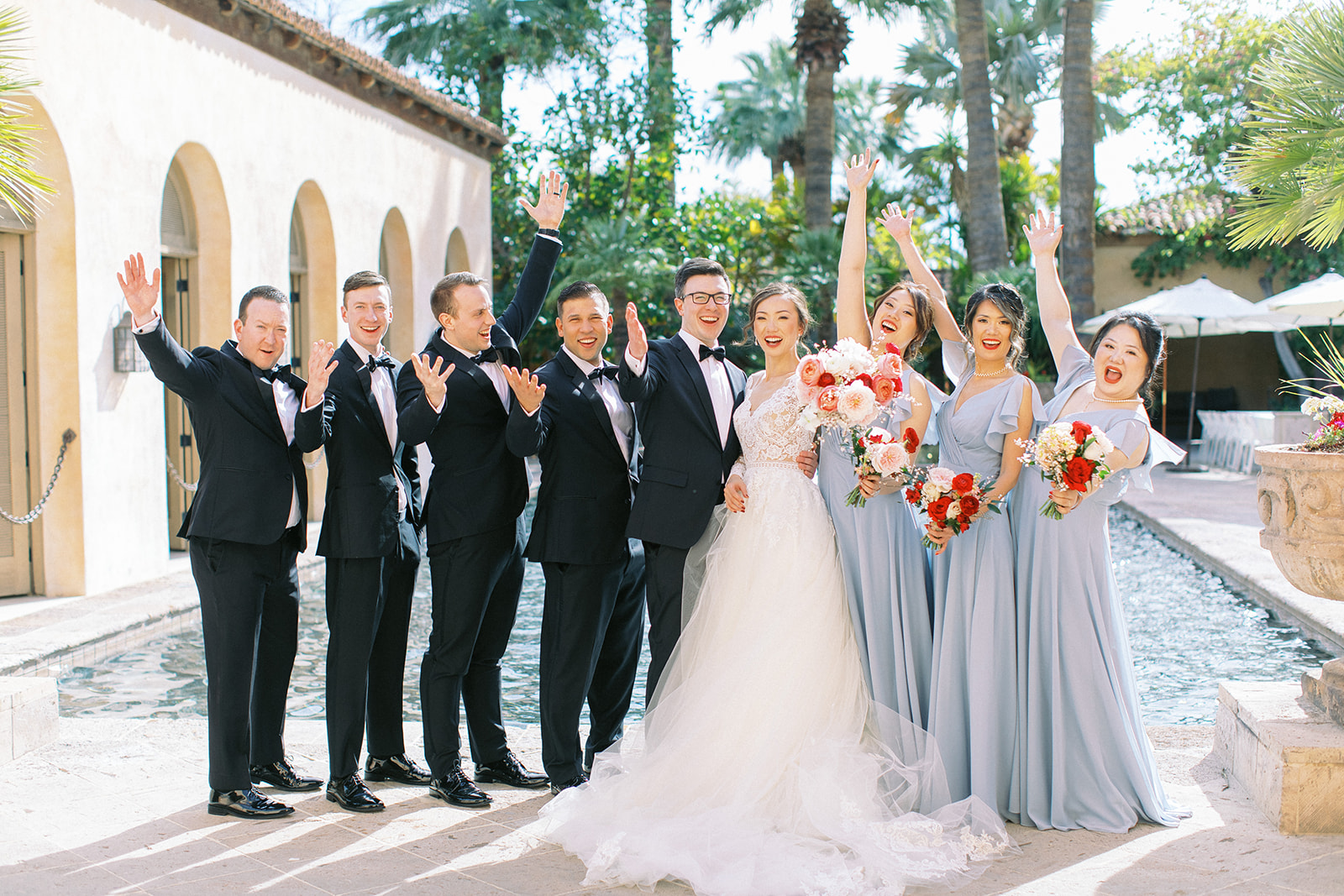 Bride and groom celebrating with bridal party in front of fountain pool at Royal Palms.