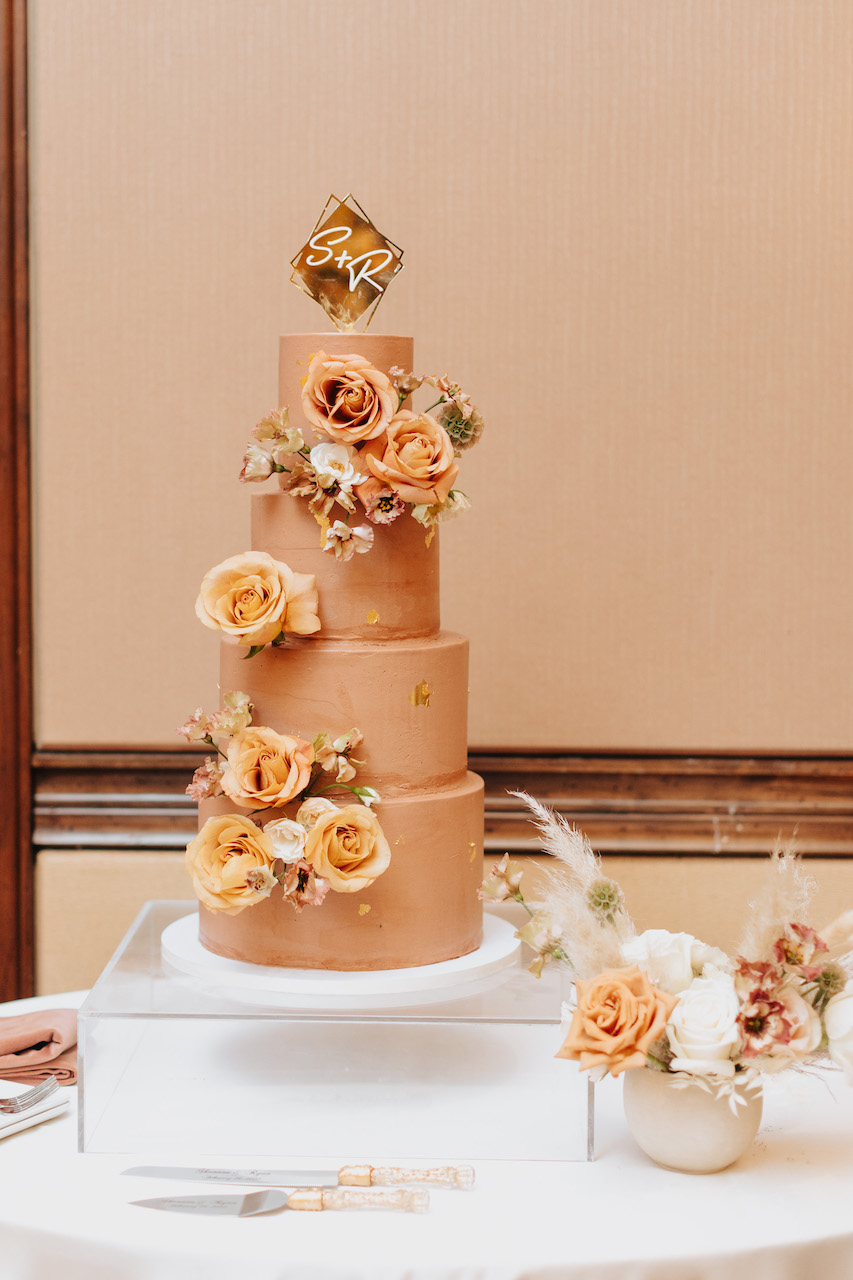 Four tiered copper wedding cake with flowers and gold flake.