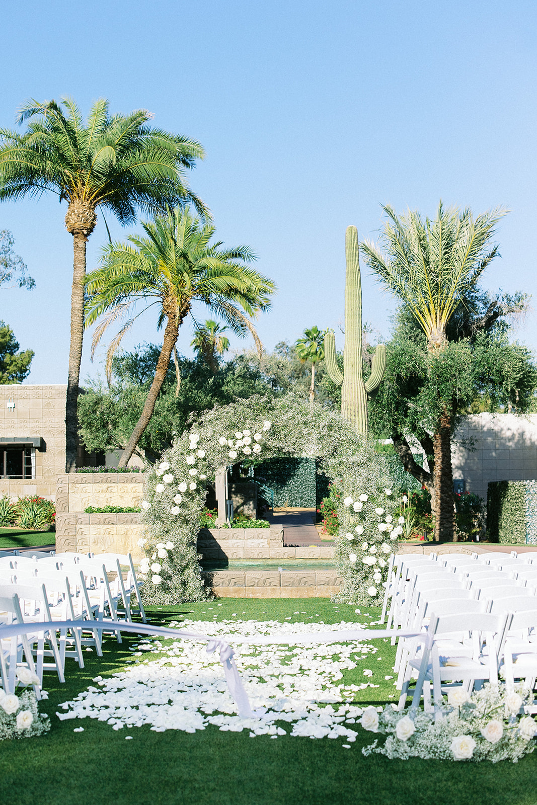 Outdoor wedding ceremony at Arizona Biltmore with white chairs, flowers.
