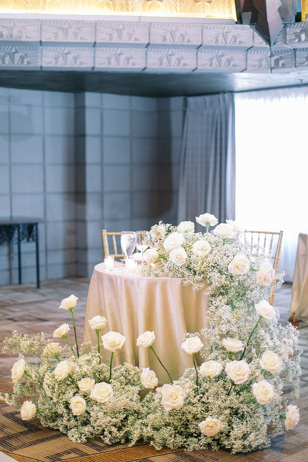 Lush, cascading baby's breath and roses garland from sweetheart table at wedding.