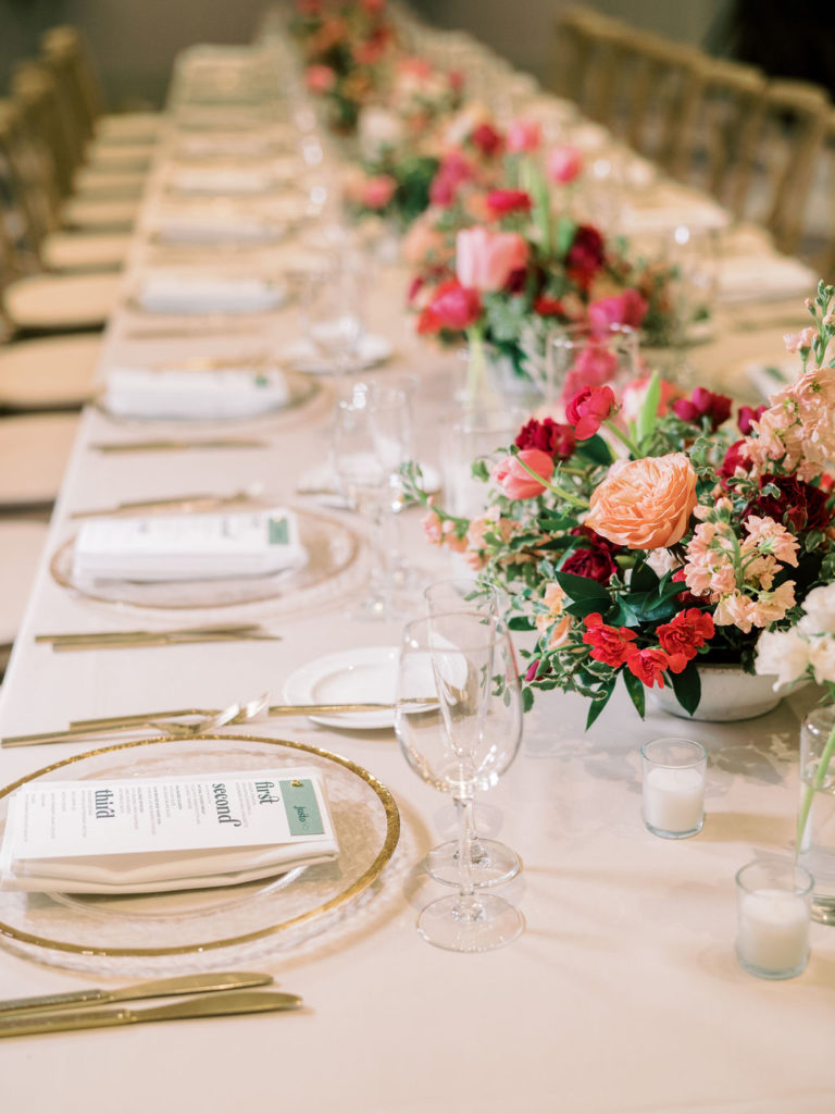 Long reception table of various floral centerpieces.