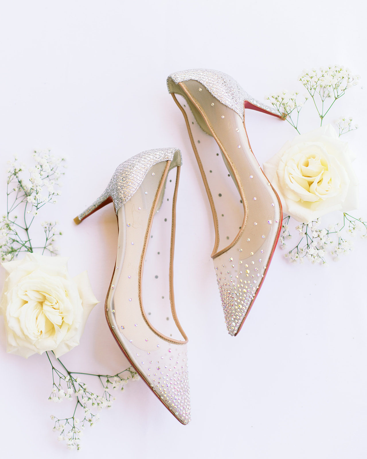 Bride's sheer shoes with sequins photographed with baby's breath and white roses.