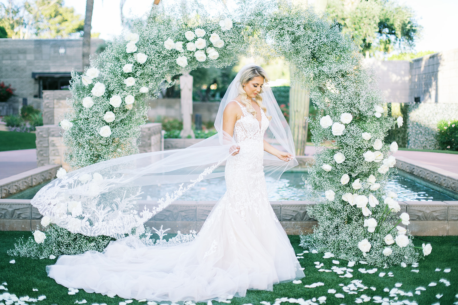 Bride in wedding dress standing in front of baby's breath arch at wedding ceremony.
