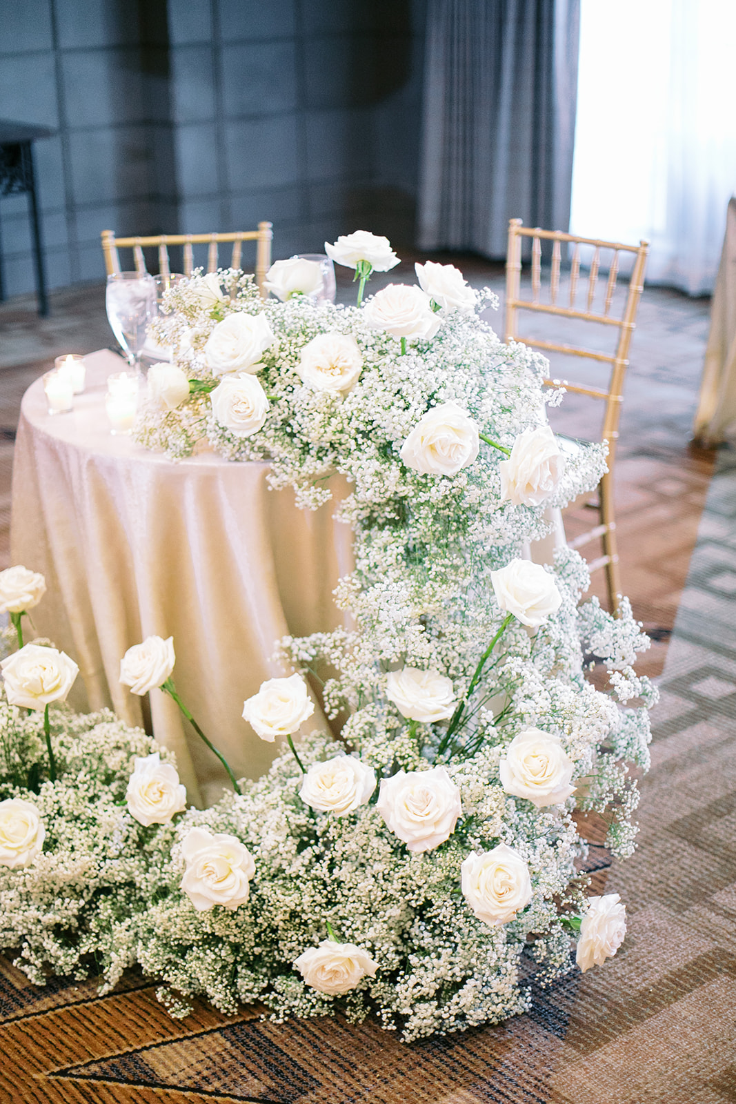 Lush, cascading baby's breath and roses garland from sweetheart table at wedding.