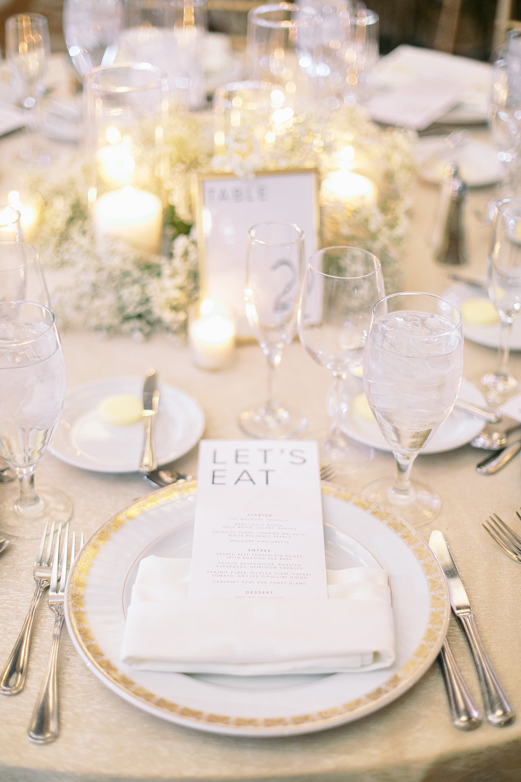 White and gold place setting at wedding reception.