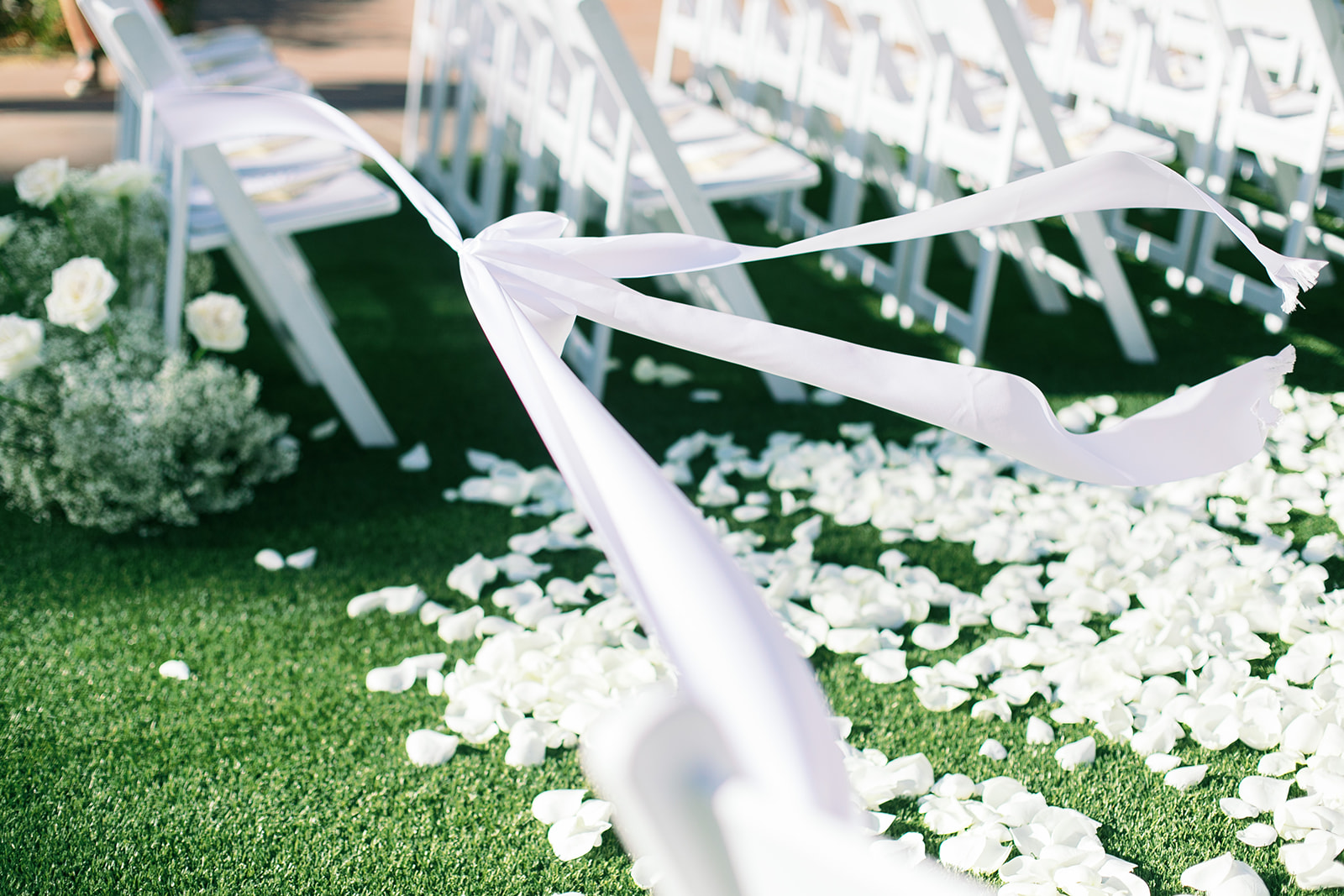 White rose petals scattered along wedding ceremony aisle.